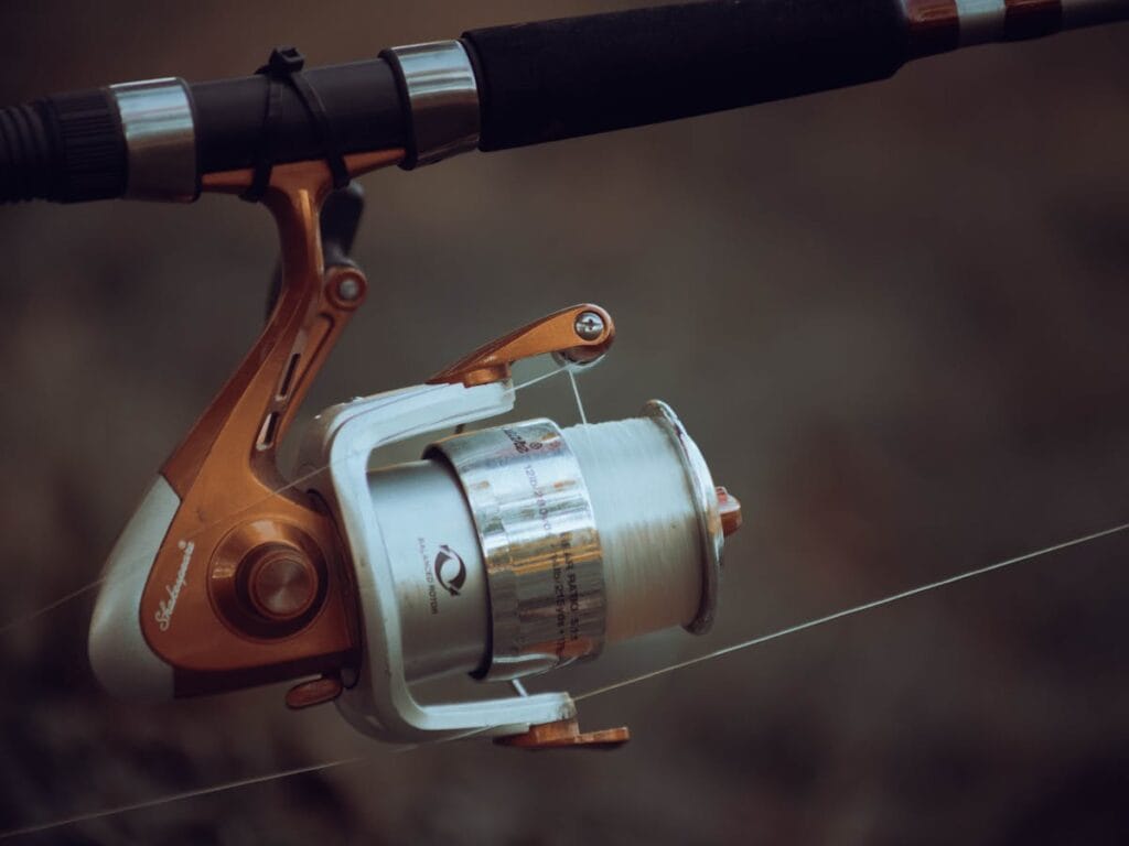 Fishing gear maintenance – close-up of a reel on a rod by the shore